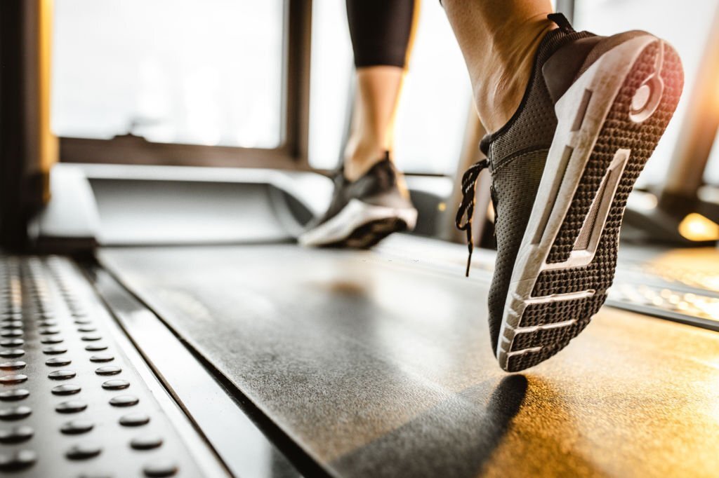 close up of sole of sneakers of unrecognizable athlete jogging on a treadmill.